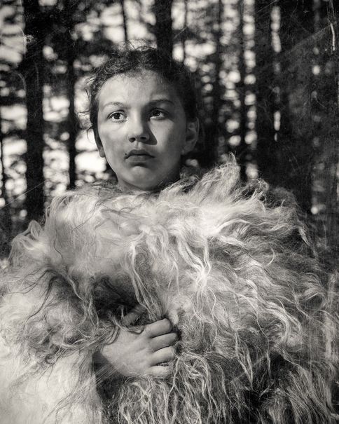 A girl wrapped in fur in a forest