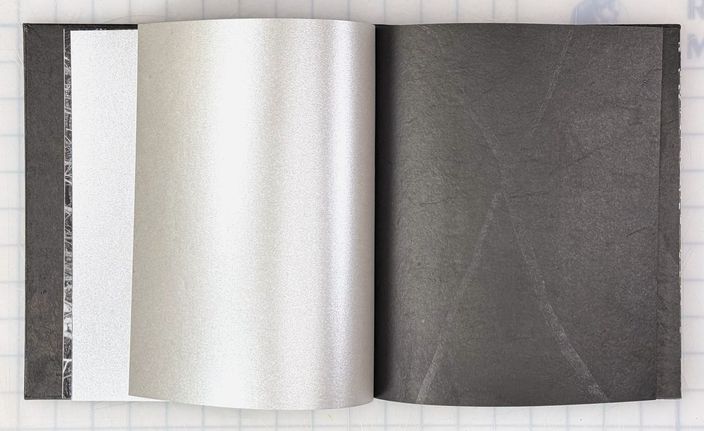 A metallic silver page lifting from the book