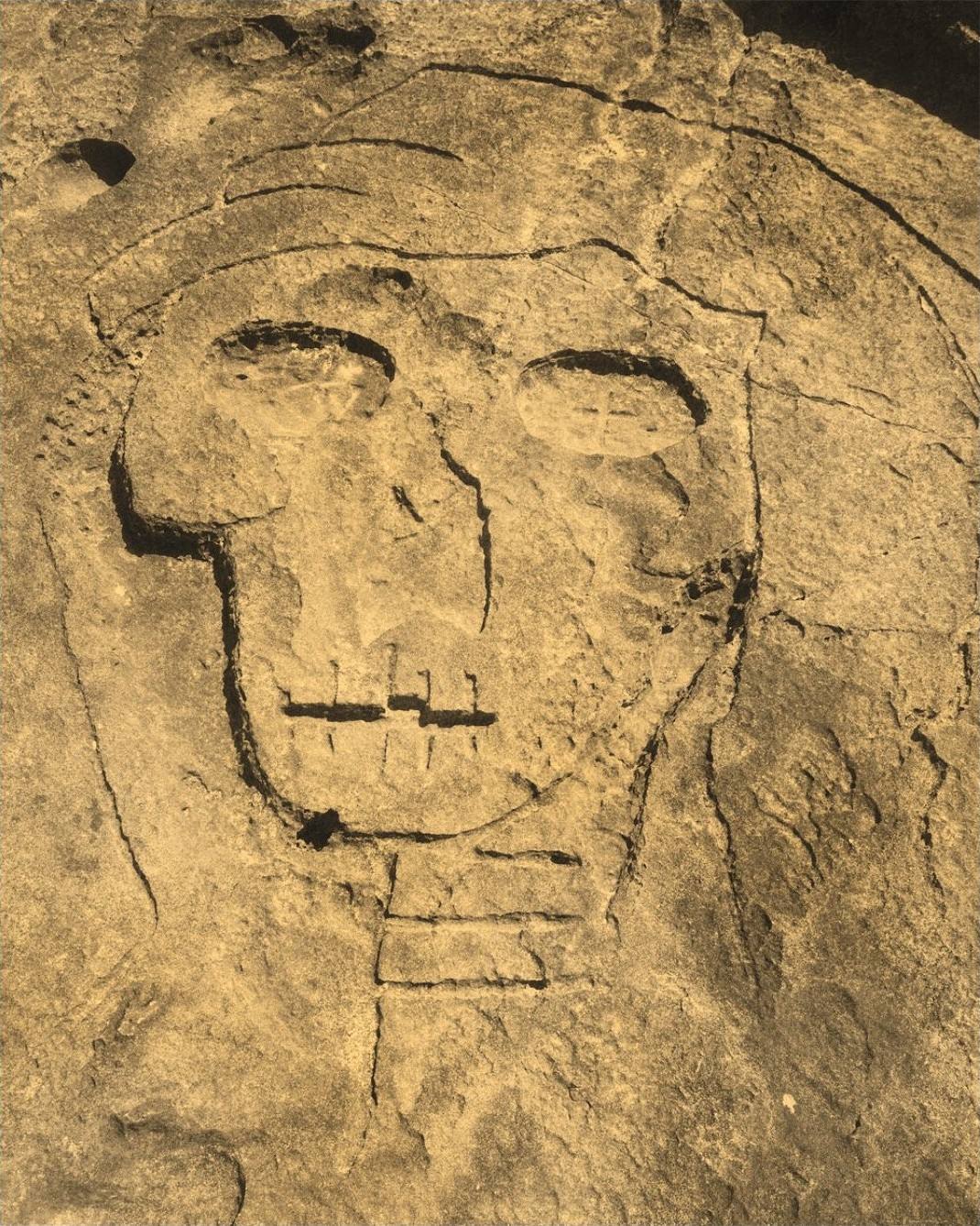 Print on gold-flecked paper: a skull carved in stone